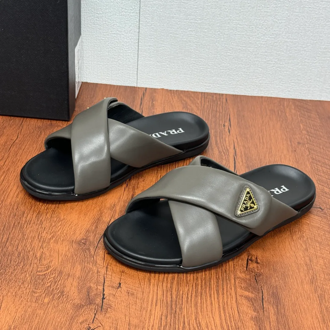 Batch 580 Prada/Prada's new men's leather cross slippers. Velcro closure can finely adjust the size. Calf leather light luxury slippers. Thick soft calf leather wraps the upper. Fat but soft rubber lazy style, soft and comfortable, excellent foot feel. Genuine leather bottom layer, cross style, with a Velcro closure buckle, easy to adjust the appropriate size, and a perfect fit for the wearing experience. The enamel gold triangle logo highlights the brand's classic features. Lightweight rubber thin sole, high foot comfort! Complete package! Size: 39-40-41-42-43-44-45 Leather shoe size Item number: 2X7132 Gray